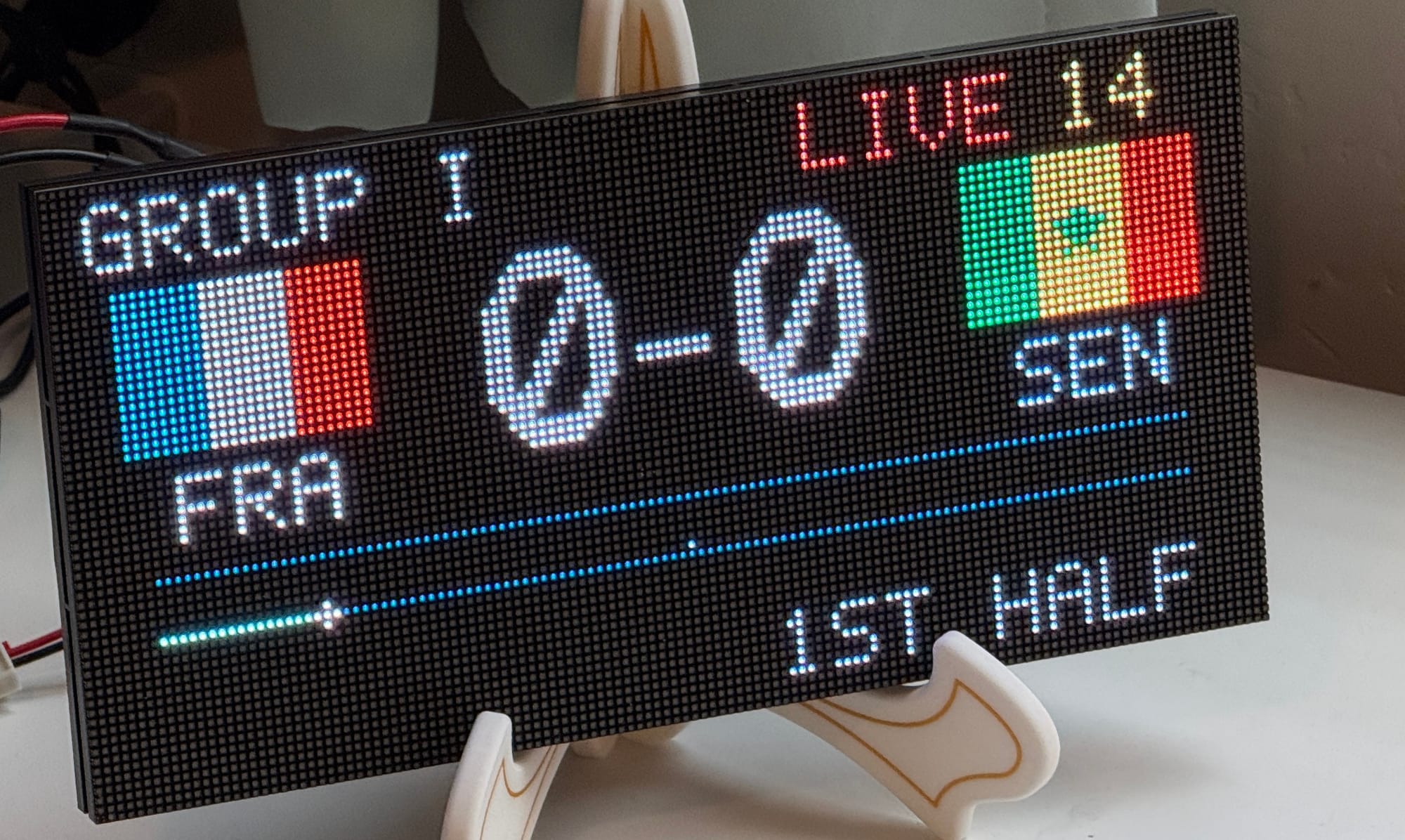 A matrix LED display showing the current score (0-0) with the flags of France and Senegal